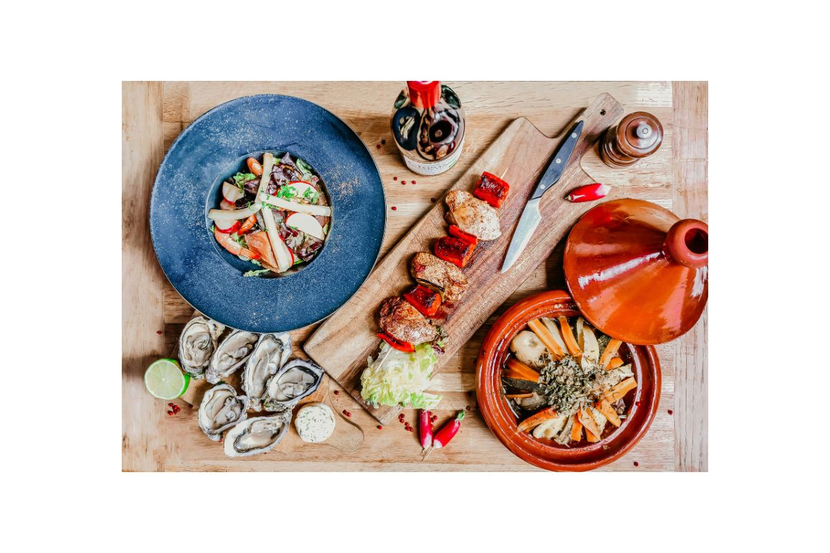 Mediterranean meat and seafood platter with grilled chicken, salad, oysters, and traditional tagine